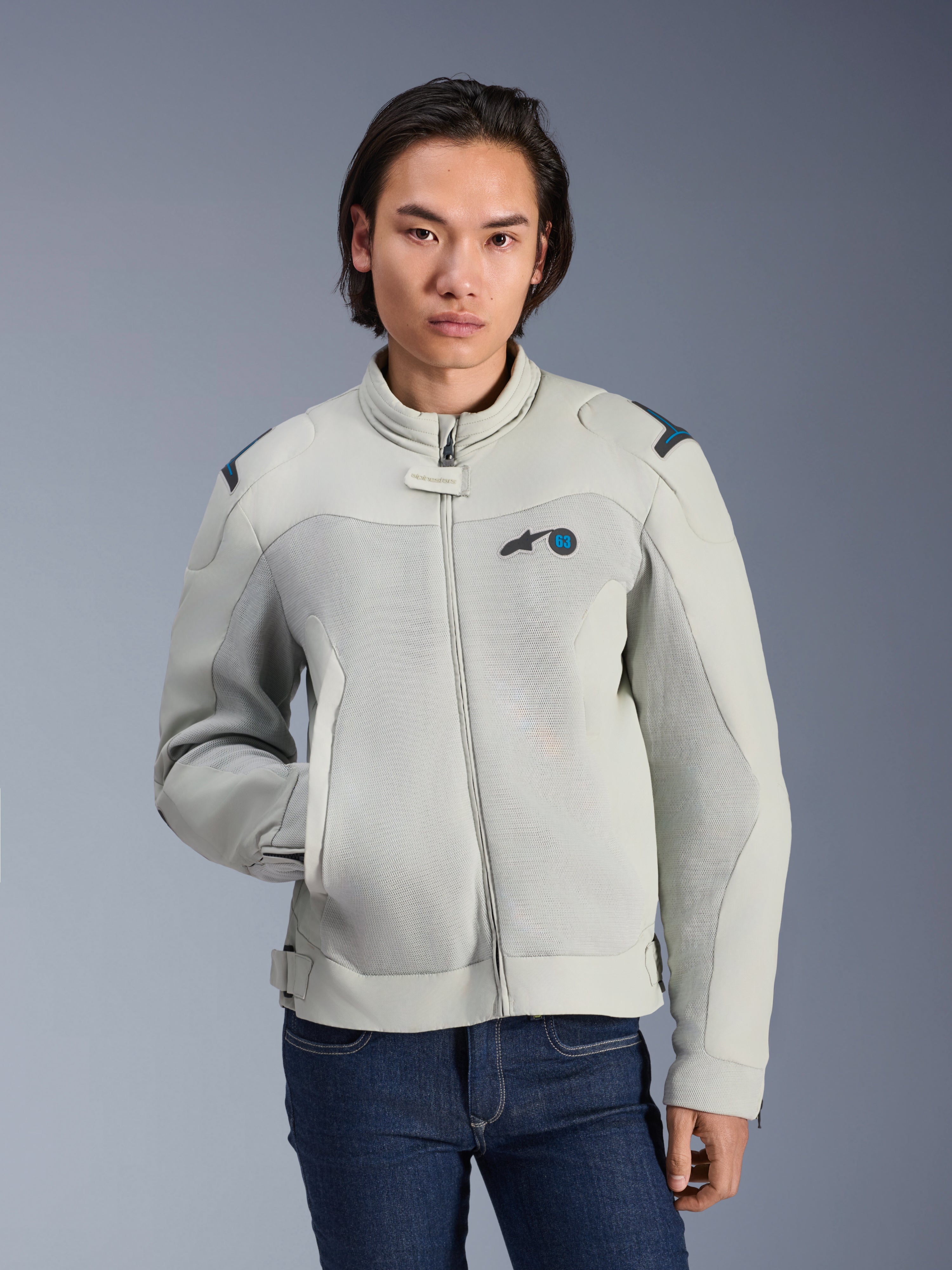 Alpinestars Circal-1 Air Jacket, Metal Gray e Methyl Blue, giacca moto urbana con pannelli in mesh per il flusso d'aria, zip frontale e colletto imbottito, indossata da un modello con jeans blu, design futuristico e sostenibile per la guida estiva