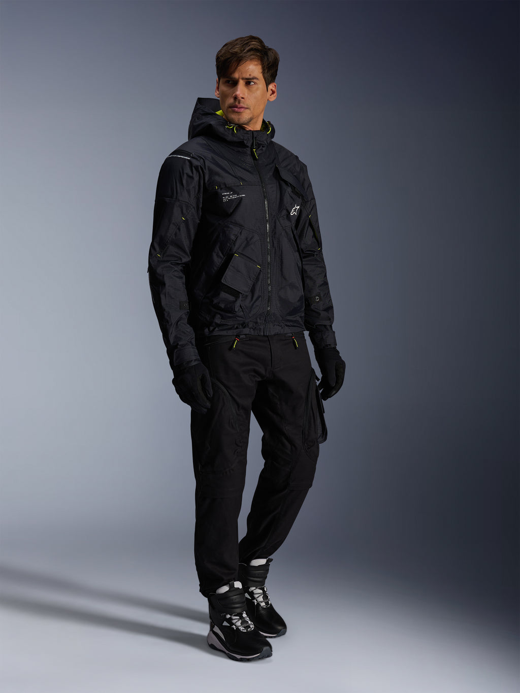 Giacca Alpinestars Mogress Air, giacca da moto urbana, nero con accenti Lime Punch e bianchi, indossata con pantaloni da moto neri, guanti e stivali bianchi e neri, design contemporaneo d'ispirazione utility.