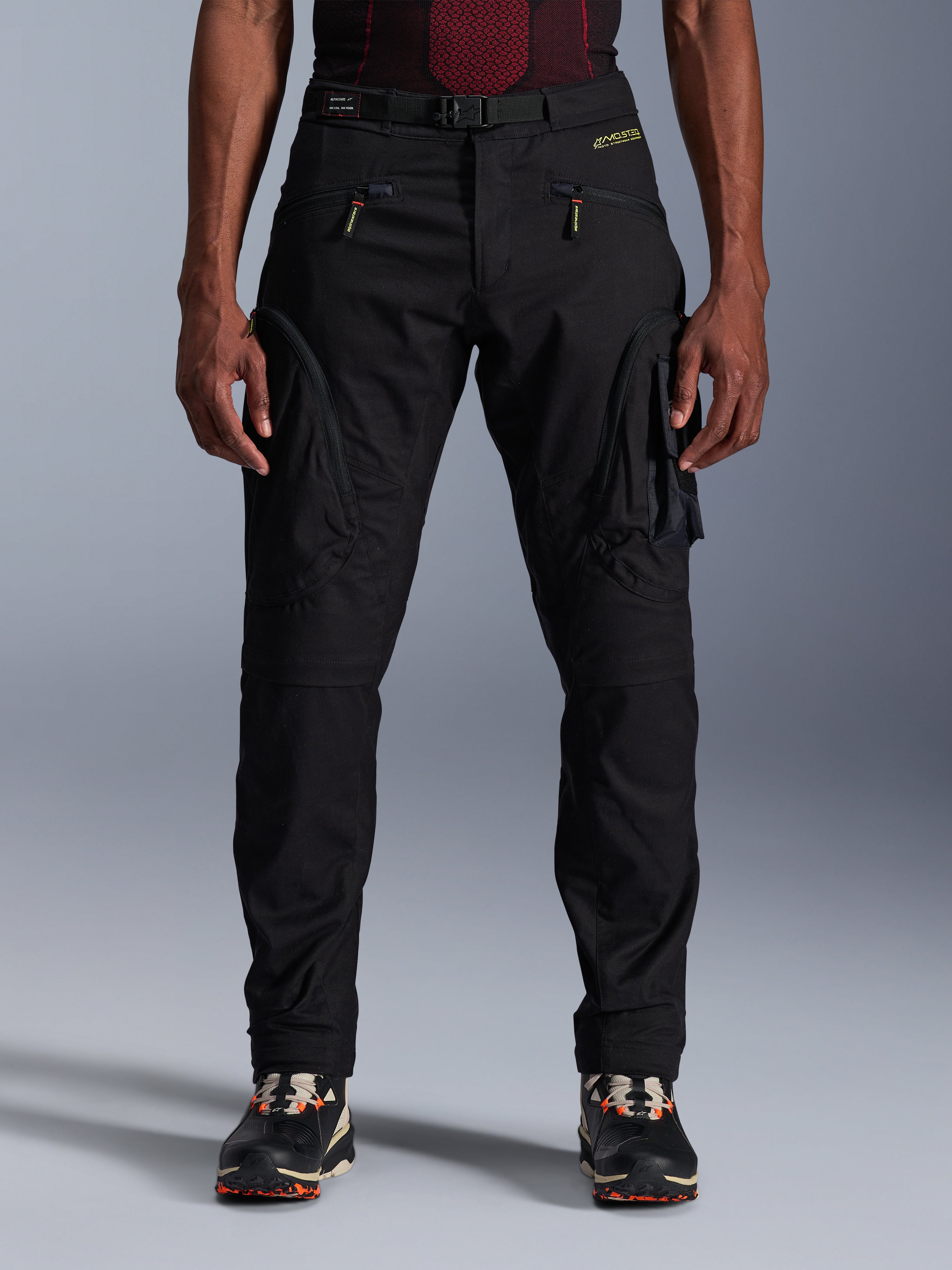 Alpinestars Acteon Pants, pantaloni da moto urban neri, vestibilità regular affusolata con tasche cargo laterali e cerniere a spirale rovesciata, cintura in vita integrata e branding giallo, abbigliamento protettivo da moto in tessuto