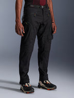 Pantaloni Alpinestars Acteon, pantaloni da moto neri, indossati da un modello, con silhouette moderna affusolata, tasche cargo con zip, cintura regolabile in vita e sneakers tecniche, abbigliamento da moto urbano