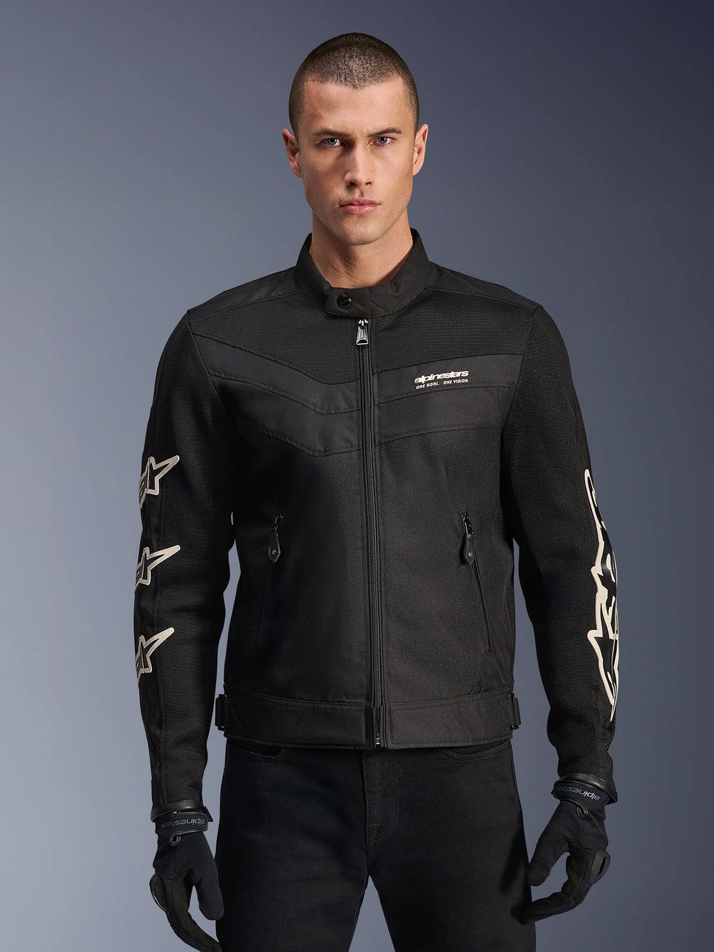 Alpinestars T-Dyno Air Jacket, giacca da moto in tessuto nera, con grafiche a stella bianche sulle maniche e logo sul petto, pannelli in mesh per la ventilazione, vestibilità biker d'ispirazione vintage, indossata con guanti e pantaloni neri