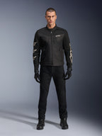 Modello maschile che indossa la giacca Alpinestars T-Dyno Air, nera, giacca da moto leggera in tessuto con mesh 3D traspirante, loghi a stella bianchi sulle maniche, abbinata a pantaloni, guanti e stivali neri, vista frontale in piedi