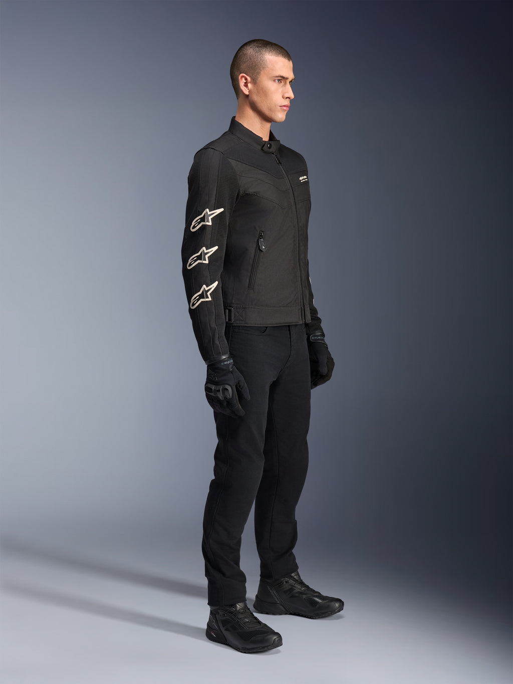Giacca Alpinestars T-Dyno Air, nero, giacca da moto in tessuto, con tre loghi Alpinestars bianchi sulla manica, indossata con pantaloni e guanti neri coordinati, abbigliamento urban riding con pannelli in rete traspirante