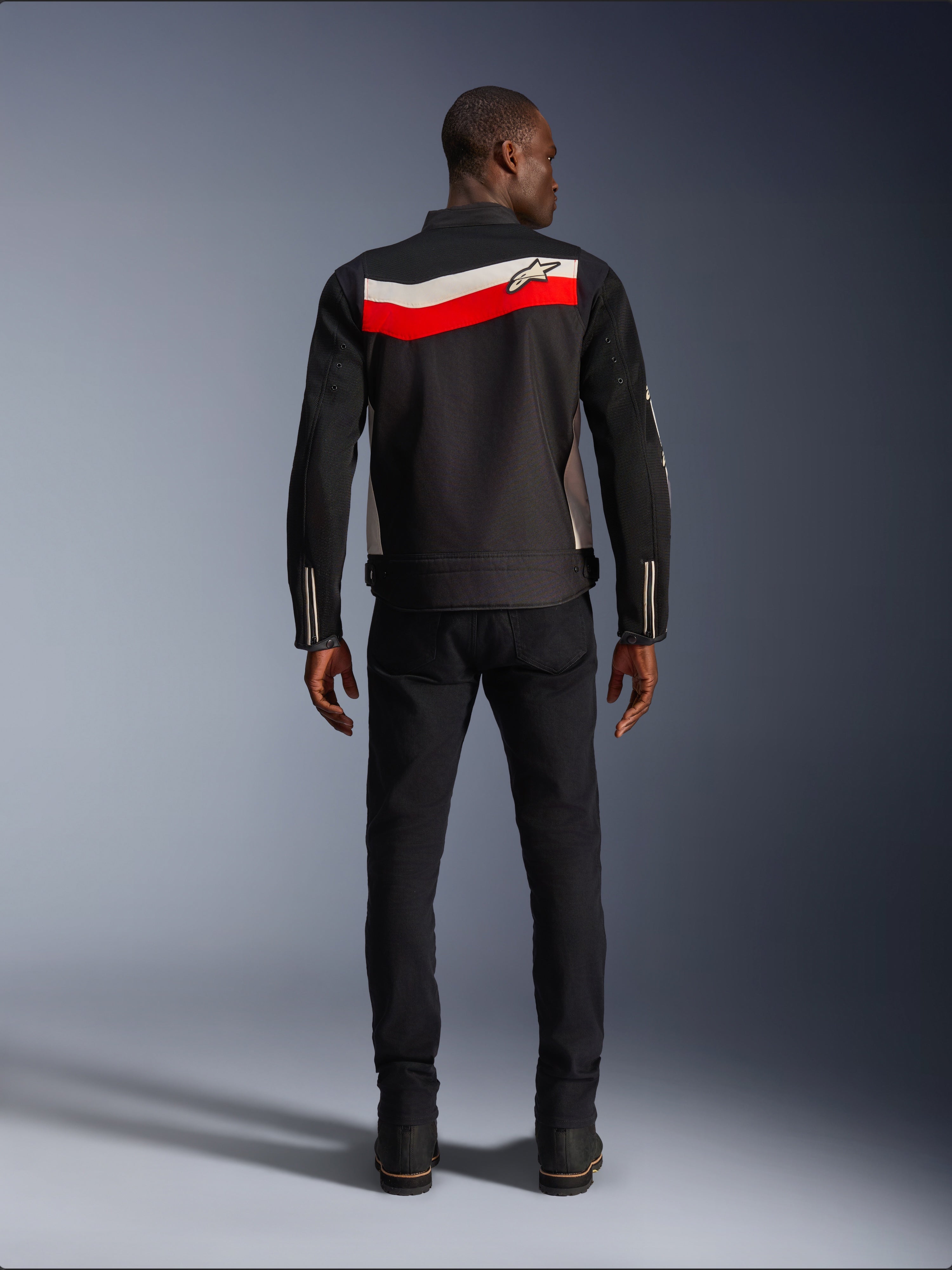 Alpinestars T-Dyno Air Jacket, giacca da moto in tessuto da uomo, vista posteriore, nera con strisce orizzontali rosso acceso ed ecru sulla schiena, logo Alpinestars sul giogo, indossata con pantaloni e stivali neri, costruzione in mesh 3D traspirante