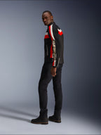 Un uomo indossa la giacca Alpinestars T-Dyno Air in nero, rosso acceso ed ecru, giacca da moto in tessuto d'ispirazione vintage con pannelli in mesh, logo vistoso sulla manica, abbinata a pantaloni e stivali neri per un moderno look da motociclista