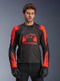 Alpinestars T-Stunt Air Jacket, giacca da moto in tessuto, nero, rosso fluo e rosso scuro, con grande logo a stella e pannelli in rete per il flusso d'aria, indossata da un modello con guanti neri