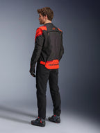 Uomo che indossa la giacca Alpinestars T-Stunt Air vista da dietro, nero, rosso fluo e rosso scuro, giacca da moto in tessuto con pannelli in mesh e design dal taglio sportivo, con vistoso marchio Alpinestars sulla parte inferiore della schiena, abbinata a pantaloni neri e stivali da guida