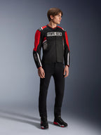 Modello che indossa la giacca Alpinestars MM93 T-SPS Air v2 in nero, rosso acceso e bianco, con marchio MM93 su petto e maniche, abbinata a pantaloni neri e stivali da moto, stile urbano sportivo con pannelli in rete per il flusso d'aria