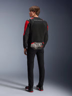 Modello di spalle che indossa la giacca Alpinestars MM93 T-SPS Air V2, nera con dettagli rosso brillante e bianchi, con scritta 'MARC MARQUEZ' e grande logo '93' sulla parte posteriore, struttura in tessuto mesh per la ventilazione, abbinata a pantaloni neri e scarpe da moto coordinate nere e rosse.