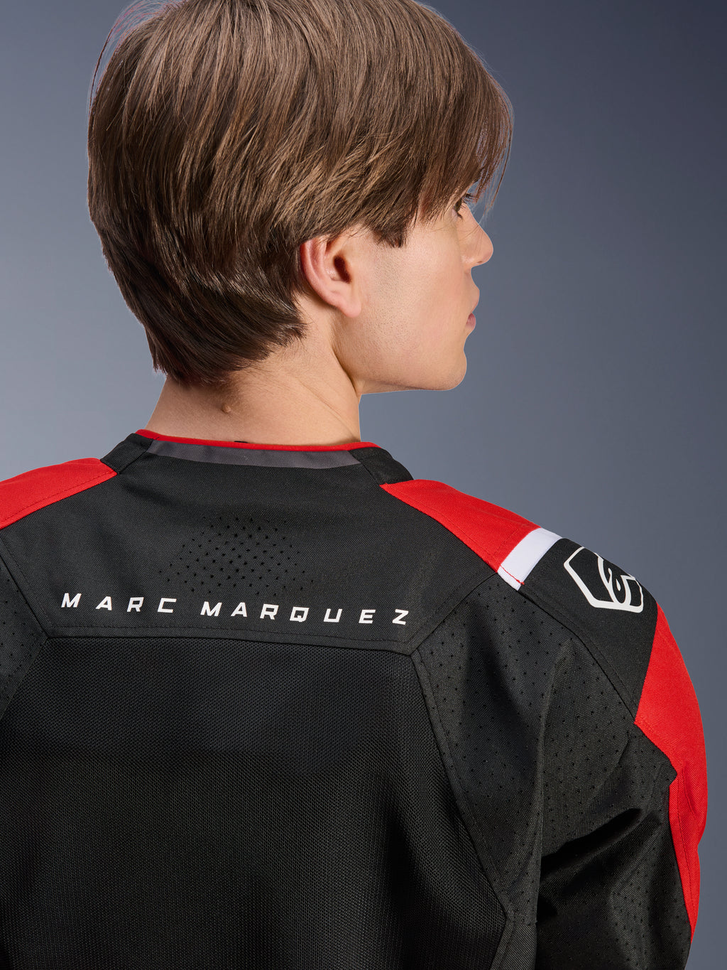 Giacca Alpinestars MM93 T-SPS Air V2, vista posteriore della parte superiore della schiena e delle spalle, nero con dettagli rosso brillante e bianco, scritta 'MARC MARQUEZ' sullo sprone, caratterizzata da pannelli in rete tecnica e logo sulla spalla, abbigliamento moto urban sport