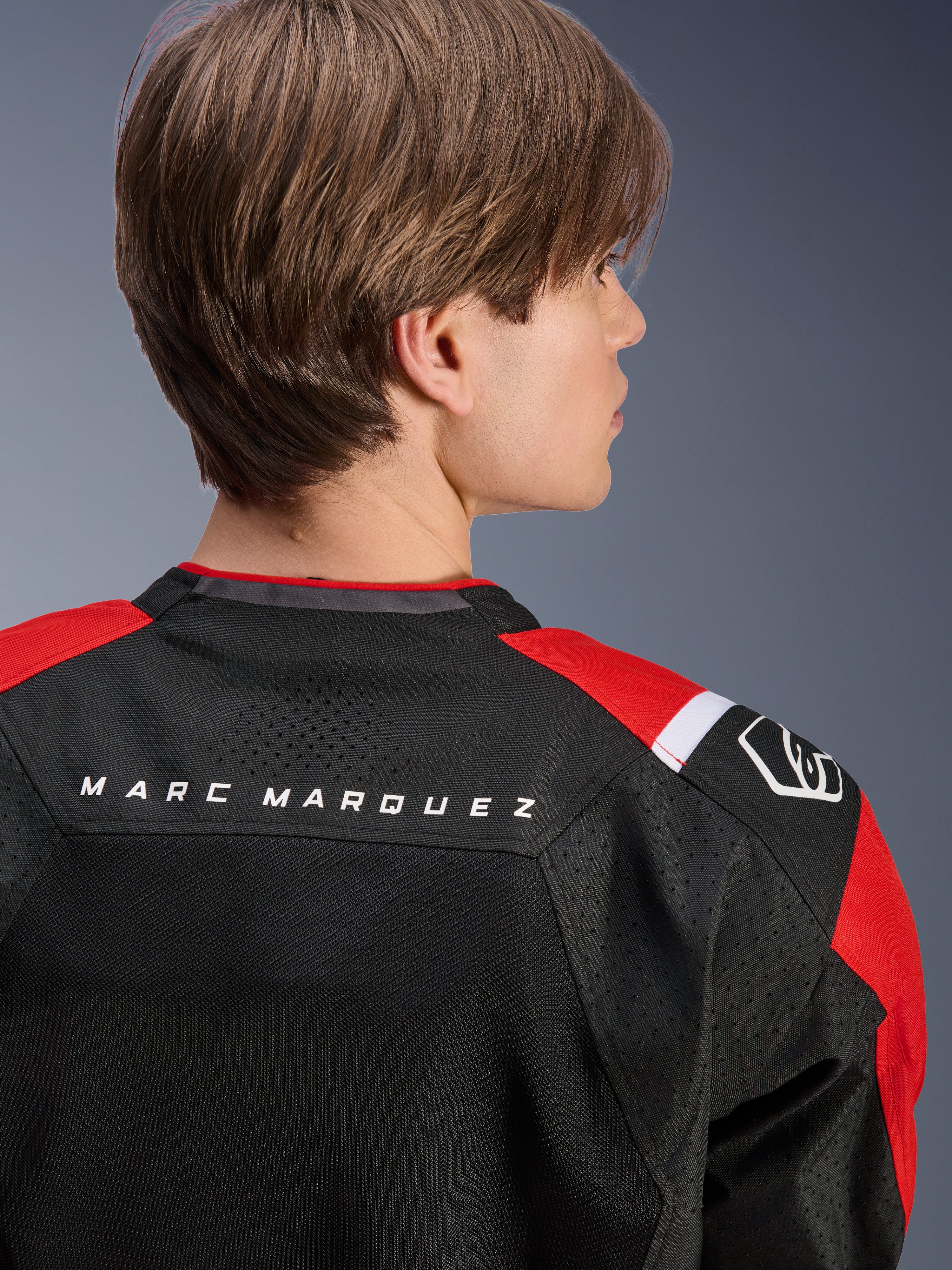 Giacca Alpinestars MM93 T-SPS Air V2, vista posteriore della parte superiore della schiena e delle spalle, nero con dettagli rosso brillante e bianco, scritta 'MARC MARQUEZ' sullo sprone, caratterizzata da pannelli in rete tecnica e logo sulla spalla, abbigliamento moto urban sport