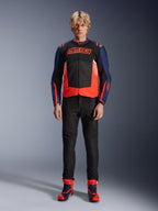 Giacca Alpinestars MM93 T-SPS Air V2, blu navy e nero con accenti rosso fluo, con il caratteristico logo MM93 sul petto, indossata con pantaloni da moto neri e stivali blu e rossi coordinati, outfit da moto urbano