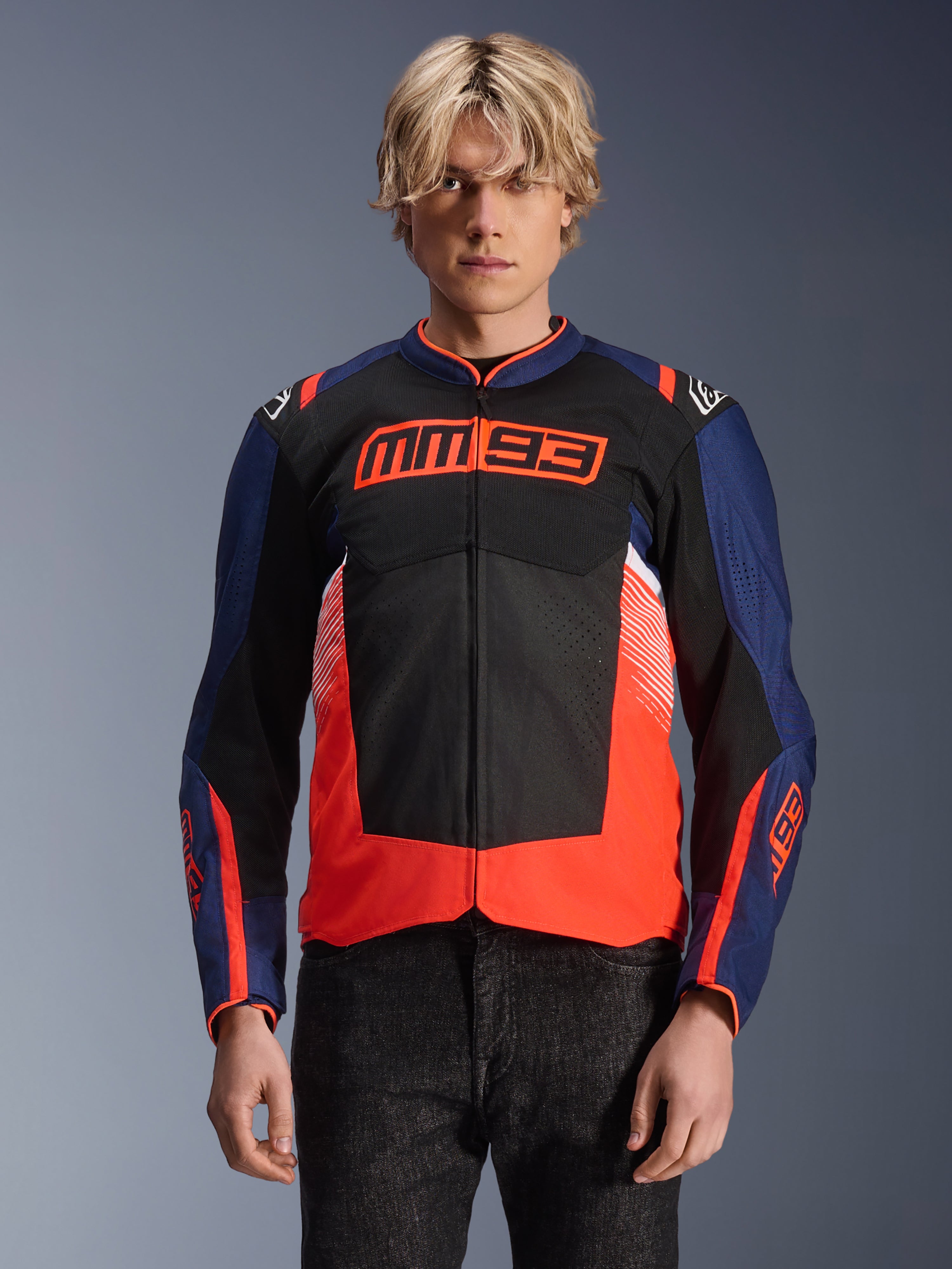 Alpinestars MM93 T-SPS Air V2 Jacket, giacca da moto in tessuto, blu navy, nero e rosso fluorescente, indossata, con vistoso logo MM93 sul petto, pannelli in rete per la ventilazione e design moderno color-block