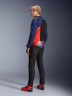 Giacca Alpinestars MM93 T-SPS Air V2, blu navy e rosso fluo, indossata da un modello vista posteriore con jeans da moto neri e scarpe coordinate rosse e blu, dotata di pannelli in mesh e logo Marc Márquez 93.