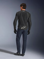Alpinestars FQ20 T-SPS Air V2 Monster Jacket, nera, vista posteriore su modello che indossa jeans blu scuro e stivali da moto neri, con un grande logo bianco sulla parte inferiore della schiena e pannelli in rete traspirante, abbigliamento tecnico sportivo urbano