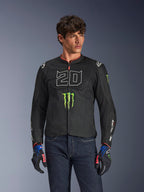 Alpinestars FQ20 T-SPS Air V2 Monster Jacket, giacca da moto nera con grande '20' bianco e logo Monster Energy verde, indossata da un modello maschile con jeans scuri e guanti coordinati, struttura in rete leggera per la guida urbana