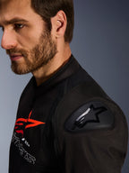 Giacca Alpinestars SMX Air, nero e rosso, dettaglio ravvicinato della protezione per spalle DFS Lite con logo a stella, indossata da un uomo con la barba, giacca da moto in tessuto per uso racing e sportivo