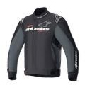 Giacca Alpinestars Monza Sport, giacca da moto in tessuto Black Tar Gray, colletto alto con scritta "ONE GOAL. ONE VISION.", loghi Alpinestars bianchi e grigi sul petto, loghi a stella sulle spalle, dettagli grafici rossi, linguette di regolazione in vita, design tecnico elegante
