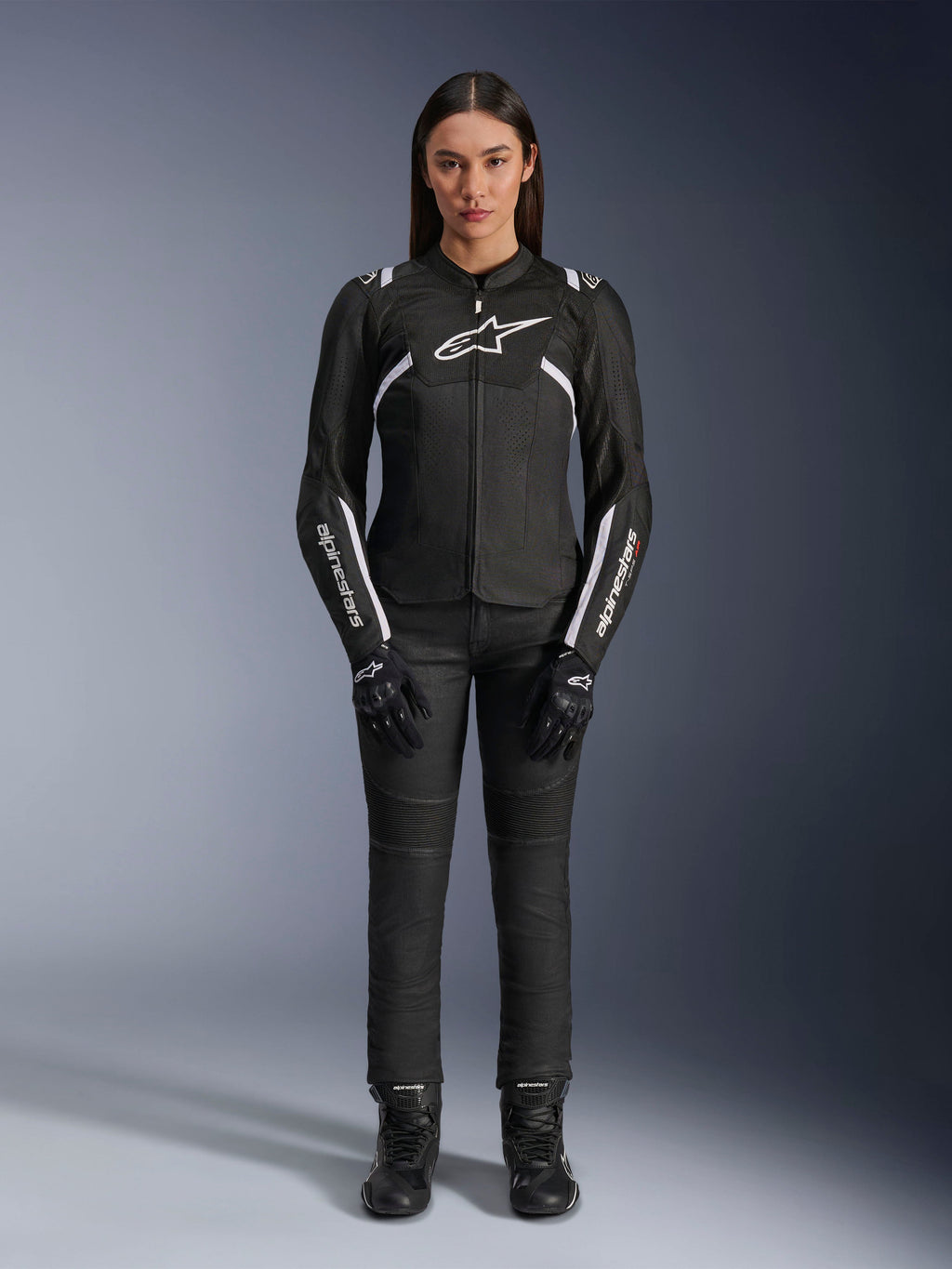 Giacca Alpinestars Stella T-Sps Air V2, giacca da moto da donna, nera e bianca, con pannelli in mesh e dettagli bianchi, indossata con pantaloni neri, guanti e stivali, vestibilità sportiva per la guida urbana