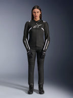 Giacca Alpinestars Stella T-Sps Air V2, giacca da moto da donna, nera e bianca, con pannelli in mesh e dettagli bianchi, indossata con pantaloni neri, guanti e stivali, vestibilità sportiva per la guida urbana