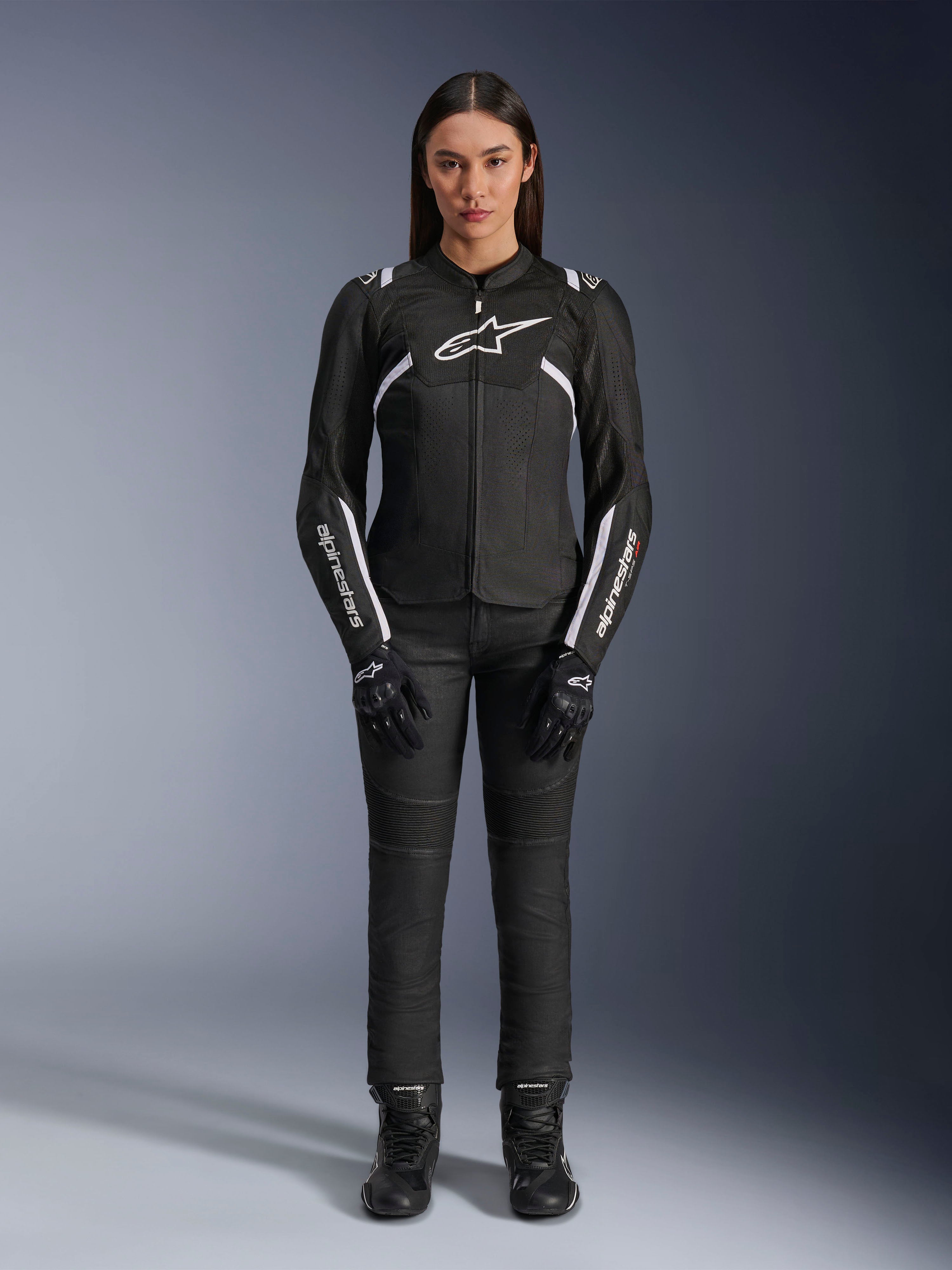 Giacca Alpinestars Stella T-Sps Air V2, giacca da moto da donna, nera e bianca, con pannelli in mesh e dettagli bianchi, indossata con pantaloni neri, guanti e stivali, vestibilità sportiva per la guida urbana