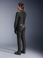 Giacca Alpinestars Stella T-Sps Air V2, nero e bianco, vista posteriore con pannelli in mesh e logo sulla parte bassa della schiena, abbinata a pantaloni da guida neri e scarpe da moto, abbigliamento tecnico sportivo da strada per donna