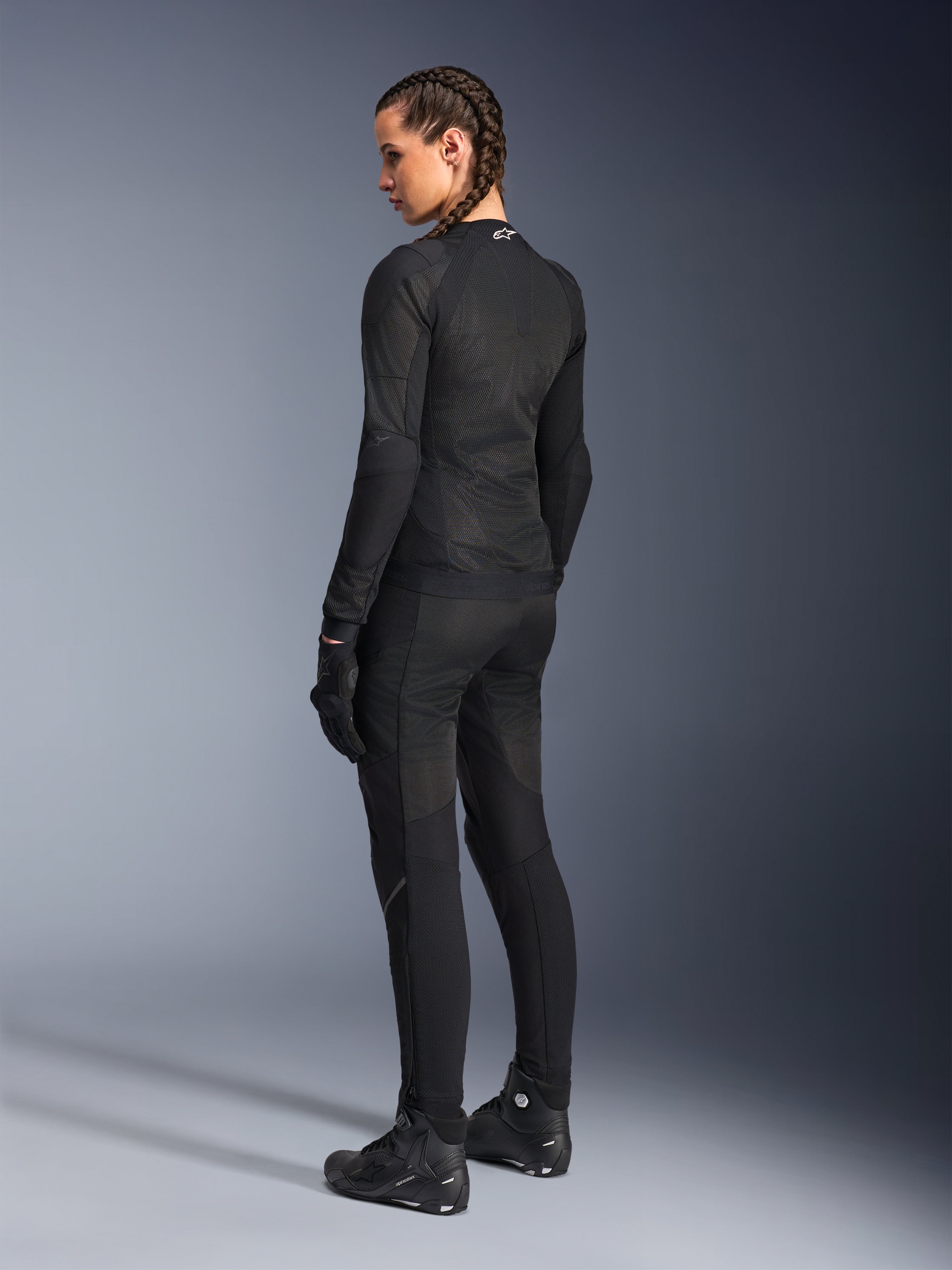 Alpinestars Giacca Stella Troop-Air da donna, nero, vista posteriore, indossata con pantaloni da moto, guanti e stivali coordinati neri, costruzione in mesh tecnico slim-fit per la guida urbana
