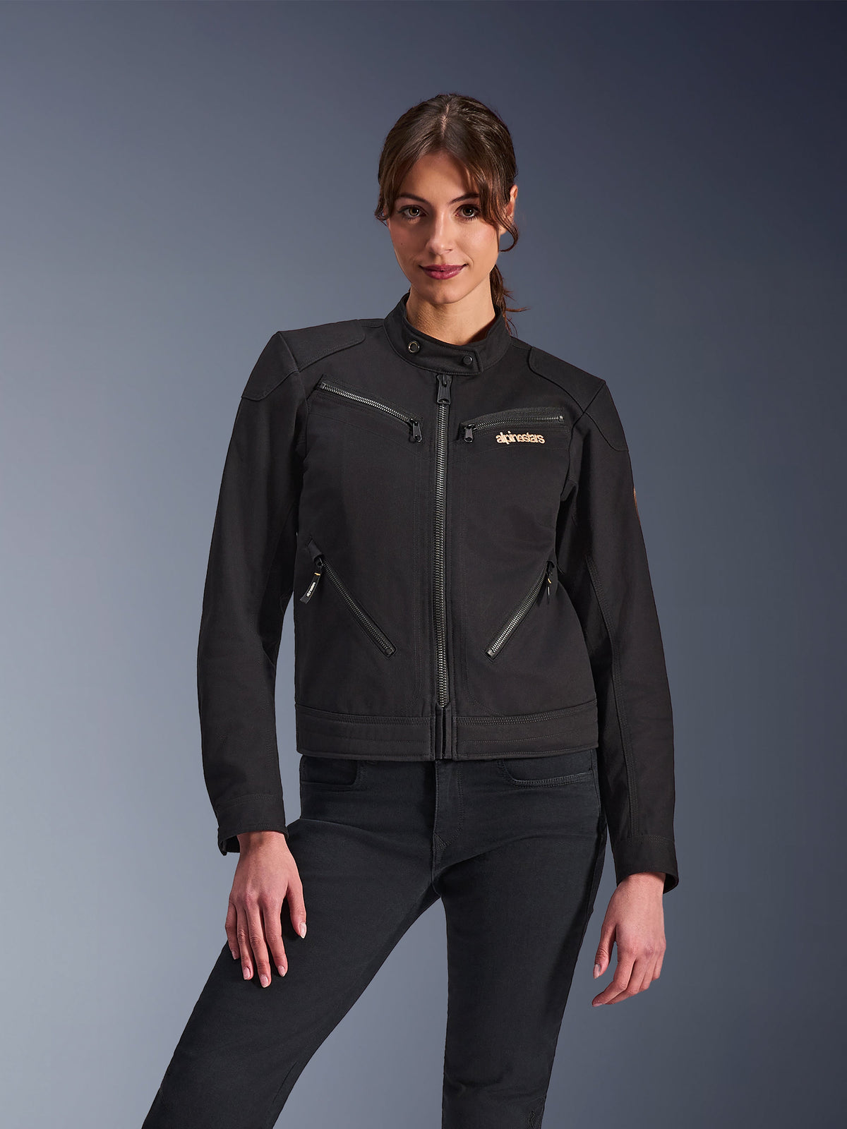 Giacca Alpinestars Stella Grace da donna, giacca da moto urbana, nero, vista frontale, con diverse tasche con cerniera e colletto con bottone a pressione, indossata con jeans neri, abbigliamento protettivo da donna dal design moderno