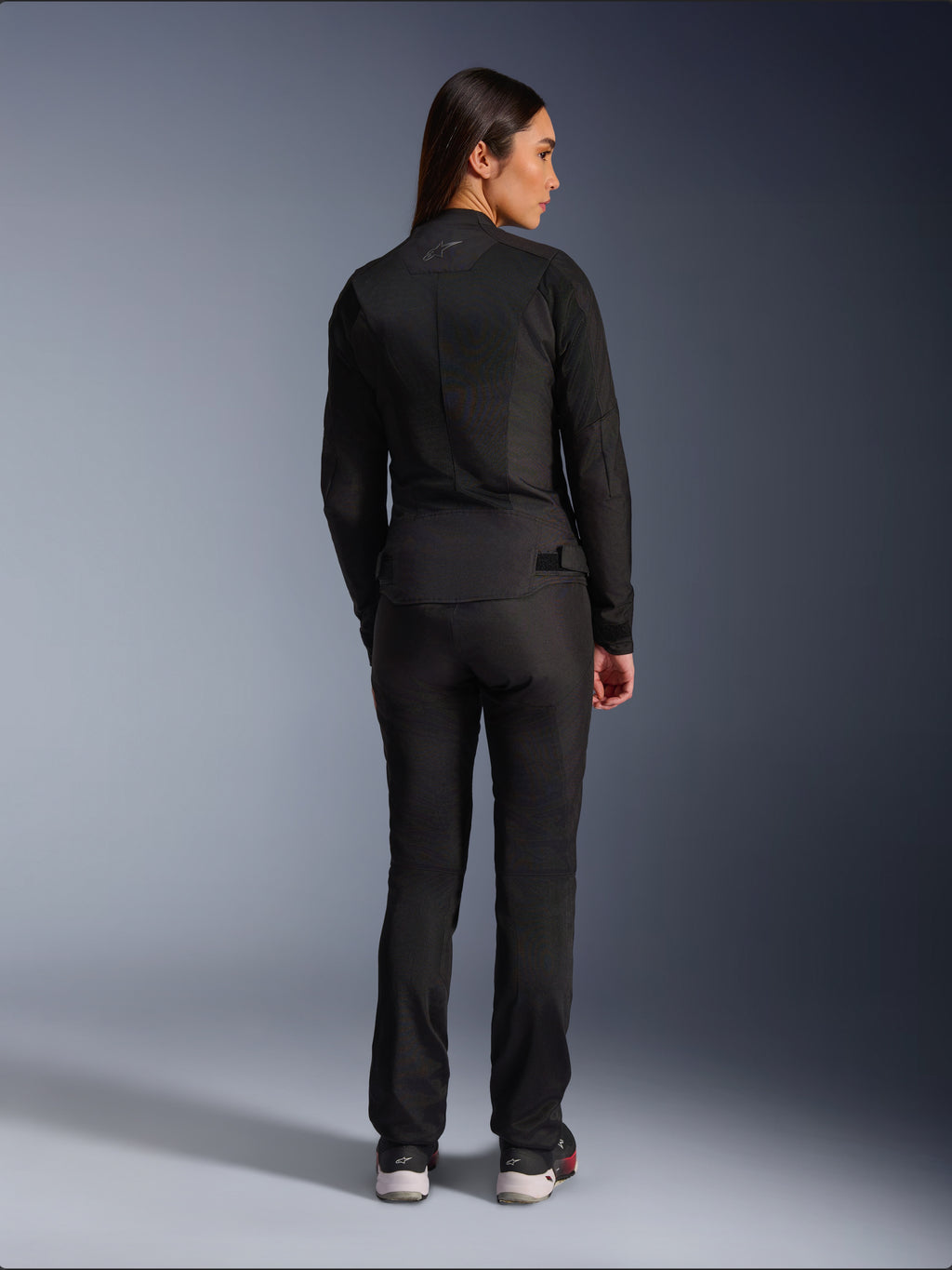 Giacca Alpinestars Stella C-1 Air, giacca da moto in tessuto per donna, nera, vista posteriore che mostra la costruzione in mesh e il logo discreto sulla parte superiore della schiena, indossata con pantaloni da moto neri coordinati, stile urban contemporaneo.