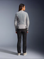 Donna che indossa la giacca Alpinestars Stella C-1 Air in Silver, vista posteriore, caratterizzata da ampi pannelli in rete tecnica per la ventilazione e un logo a stella riflettente, abbinata a pantaloni da moto neri e sneakers bianche, abbigliamento da moto urban contemporary