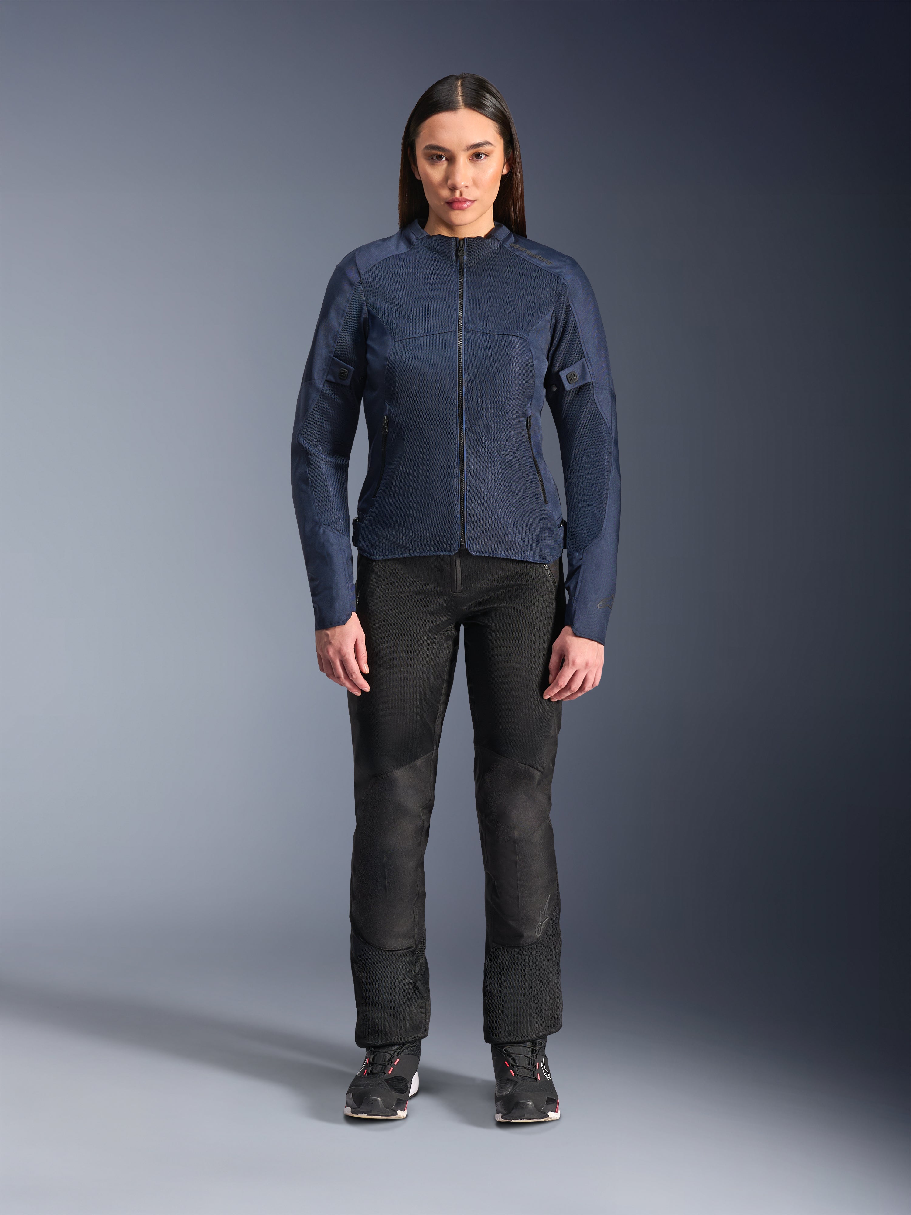 Modella con giacca Alpinestars Stella C-1 Air in blu, giacca da moto urban con pannelli in rete tecnica, abbinata a pantaloni tecnici neri e sneakers nere, vista frontale in studio