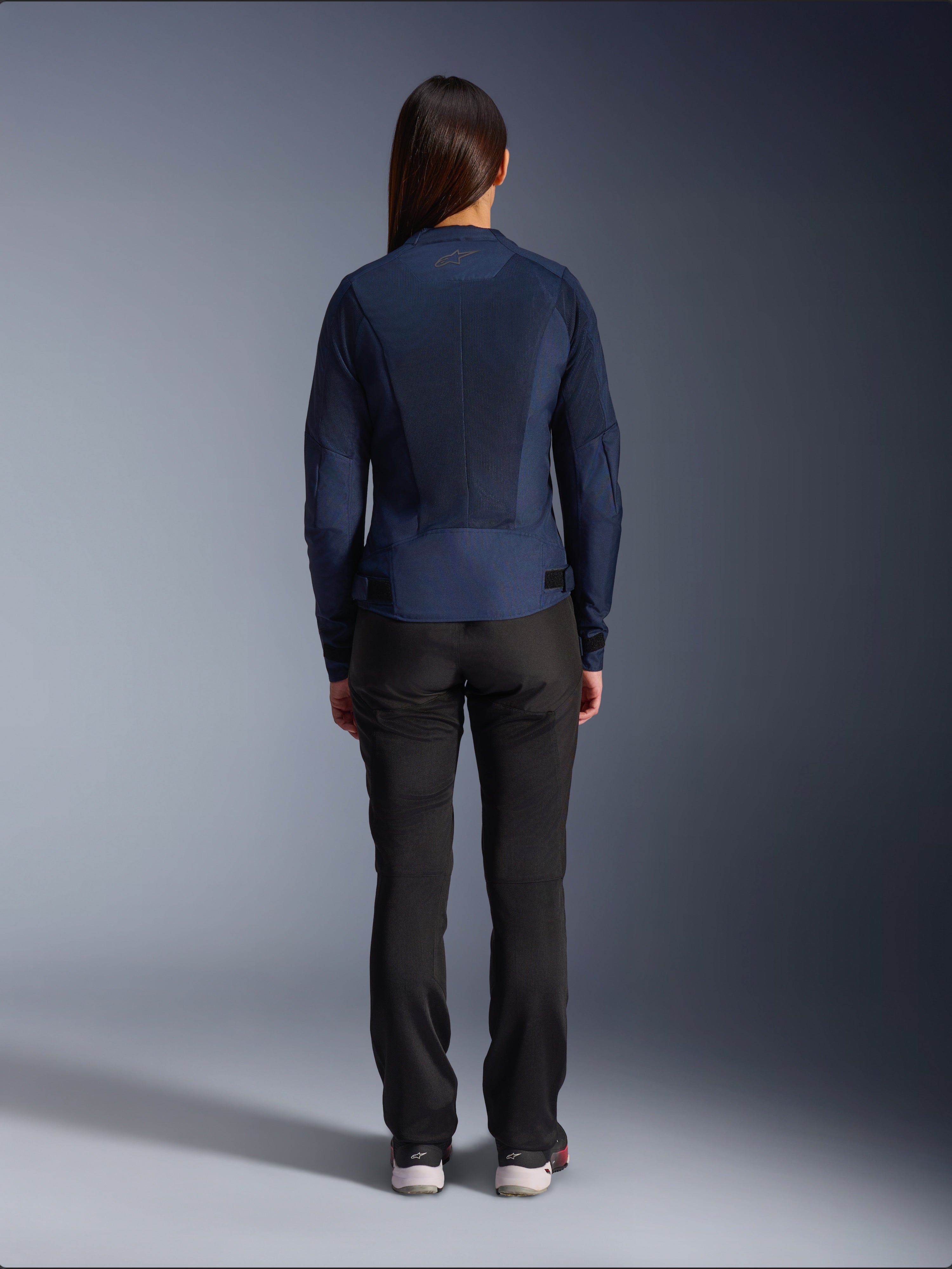 Giacca Alpinestars Stella C-1 Air, giacca da moto in tessuto da donna, blu navy, vista posteriore con ampi pannelli in mesh per la ventilazione e logo Alpinestars sul collo, abbinata a pantaloni da moto neri per un look urbano moderno