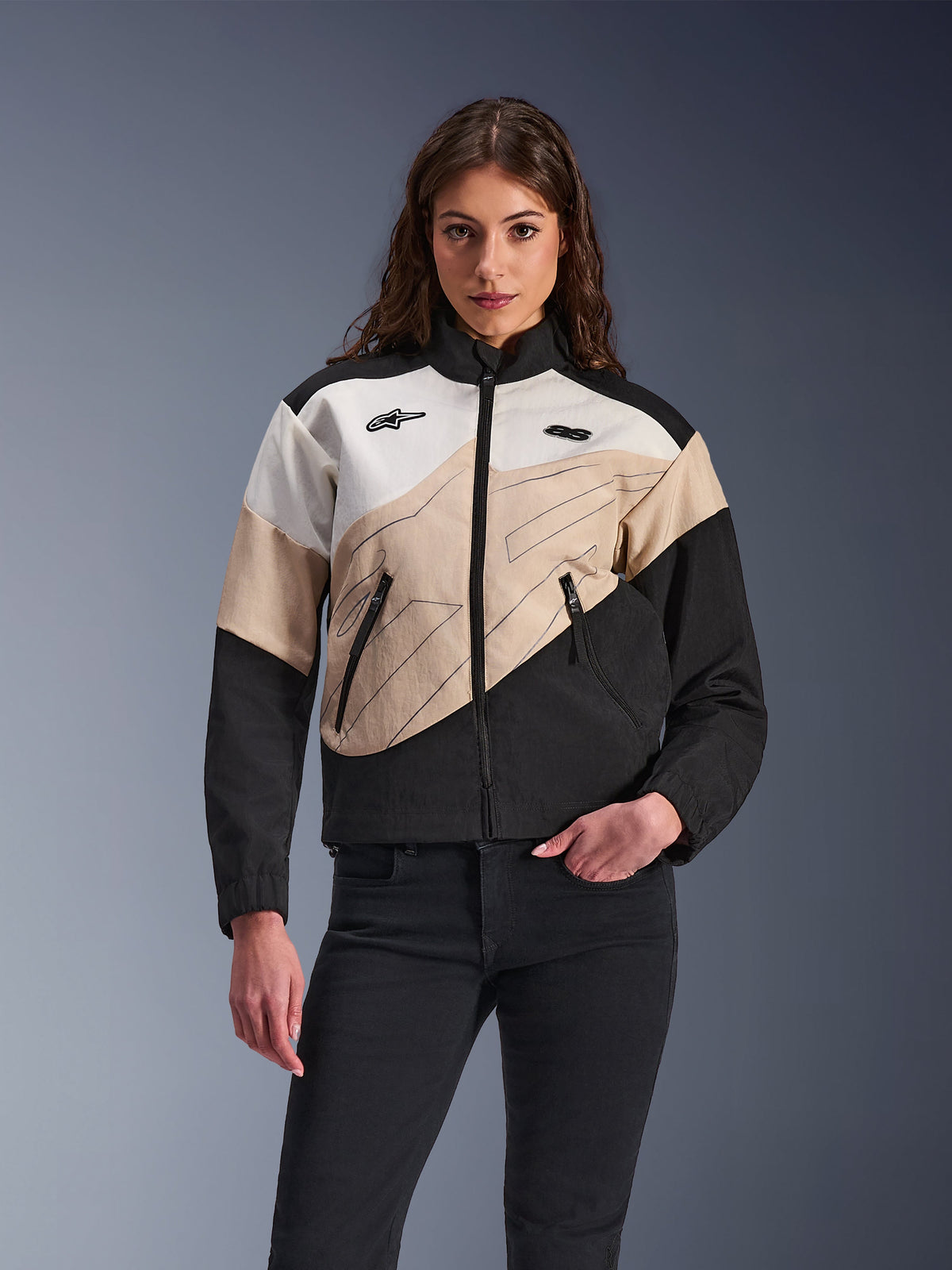Alpinestars Stella Moshell Jacket, giacca da moto urbana da donna, design color-block asimmetrico in nero, sabbia e bianco sporco, con cerniera frontale e tasche per le mani con zip, indossata con pantaloni neri per un look streetwear contemporaneo.