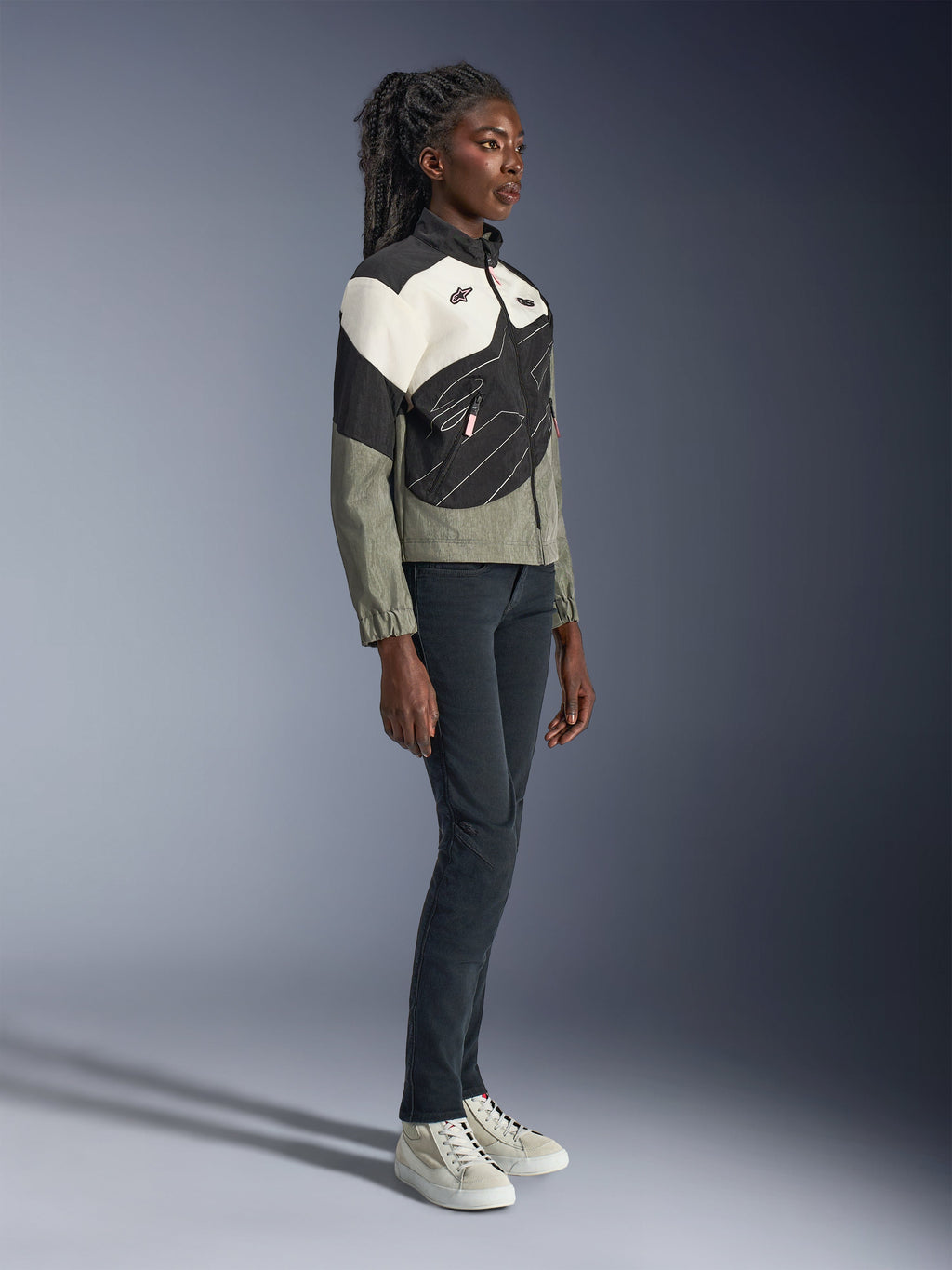Giacca Alpinestars Stella Moshell, giacca da moto urban da donna, grigio, nero e bianco sporco con accenti rosa, vista a figura intera di una modella che indossa pantaloni scuri e sneakers, design contemporaneo ispirato allo streetwear per la guida urbana