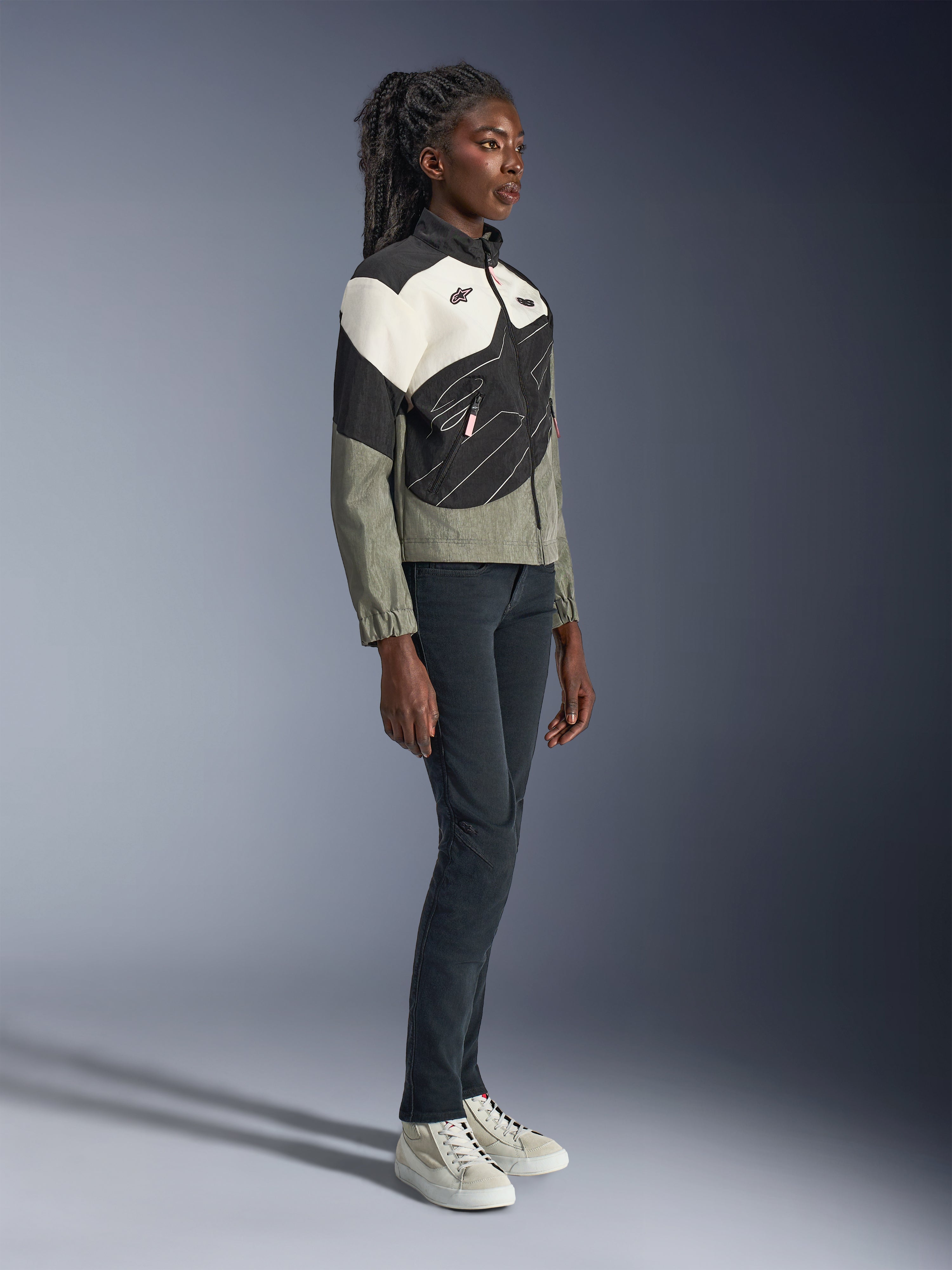 Giacca Alpinestars Stella Moshell, giacca da moto urban da donna, grigio, nero e bianco sporco con accenti rosa, vista a figura intera di una modella che indossa pantaloni scuri e sneakers, design contemporaneo ispirato allo streetwear per la guida urbana