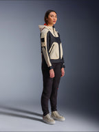 Giacca Alpinestars Molly Air in Black Almond, indossata da una motociclista con pantaloni neri e sneakers alte color crema, design bicolore con pannelli neri e beige, cappuccio integrato e stile urbano contemporaneo.