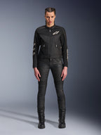 Modella con giacca Alpinestars Stella T-Dyno Air, giacca da moto da donna in nero, con pannelli in rete 3D e loghi Astars bianchi, abbinata a pantaloni da moto slim-fit neri e stivali stringati neri, stile urban riding