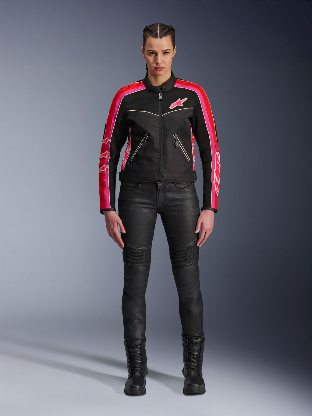 Motociclista che indossa la giacca Alpinestars Stella T-Dyno Air, nera con accenti rosso brillante e fucsia, abbinata a pantaloni da moto neri e stivali stringati, con pannelli in rete 3D, vestibilità su misura e loghi a stella rosa, abbigliamento da moto urban