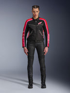 Motociclista che indossa la giacca Alpinestars Stella T-Dyno Air, nera con accenti rosso brillante e fucsia, abbinata a pantaloni da moto neri e stivali stringati, con pannelli in rete 3D, vestibilità su misura e loghi a stella rosa, abbigliamento da moto urban