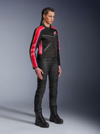 Alpinestars Stella T-Dyno Air Jacket, giacca da moto da donna, nero con strisce rosso acceso e fucsia sulle maniche, indossata con pantaloni da moto e stivali neri, design in rete d'ispirazione vintage per la guida urbana