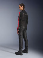 Donna che indossa la giacca Alpinestars Stella T-Dyno Air in Nero Rosso Brillante Fucsia, abbinata a pantaloni da moto neri e stivali neri, vista di profilo che mette in risalto le grafiche rosse e fucsia sulle maniche e la vestibilità da moto su misura.