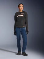 Motociclista con giacca Alpinestars Stella SMX Air, nera con loghi bianchi e rosso fluo, abbinata a pantaloni da moto in denim blu e guanti neri, giacca sportiva in tessuto ventilato per uso stradale