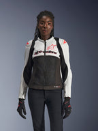 Alpinestars Stella SMX Air Jacket, giacca da donna, grigio ghiaccio, nero e corallo fluo, con struttura in rete e pannelli traforati, indossata da una modella con guanti e pantaloni da moto neri, vista frontale.