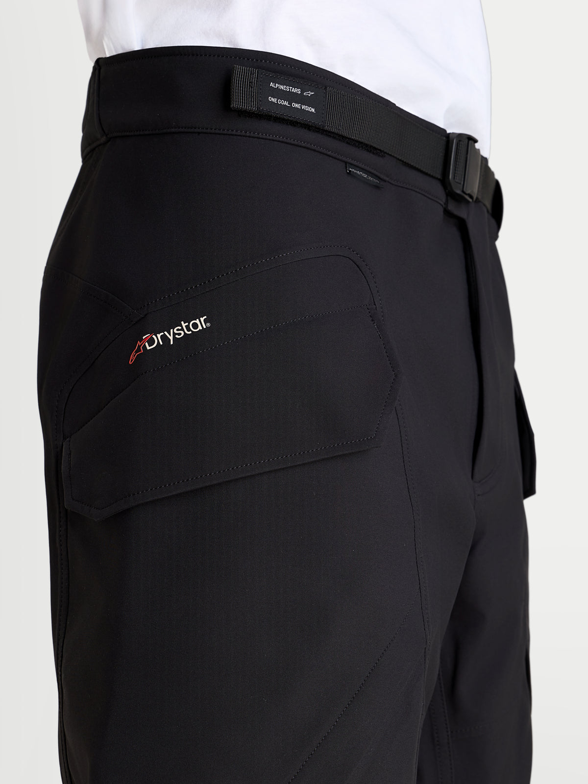Alpinestars Juggernaut V 2 Drystar Pantaloni, pantaloni da moto urban impermeabili da uomo, colore nero, vista in primo piano che evidenzia il logo Drystar, la tasca cargo e la cintura con fibbia magnetica regolabile
