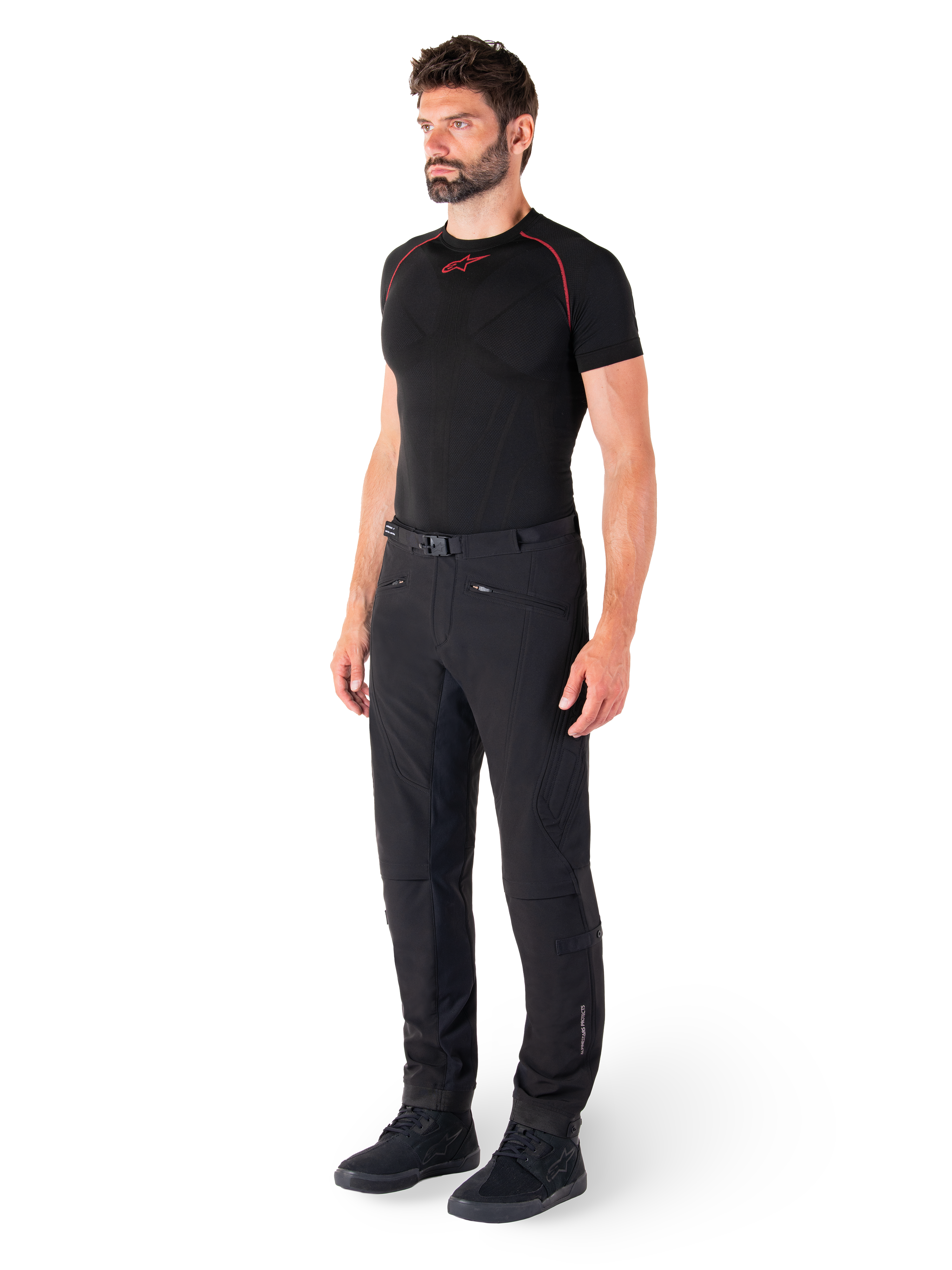 Pantaloni Alpinestars Alden, pantaloni da moto urban, nero, tessuto softshell vestibilità regular, indossati da un modello con base layer nero e scarpe da moto, con cintura in vita con chiusura magnetica e tasche con zip.