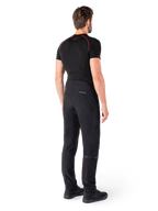 Alpinestars Alden Pants, Nero, pantaloni da moto urban visti dal retro su un modello, indossati con un base layer nero a maniche corte e scarpe da guida nere, caratterizzati da dettagli trapuntati e marchio MO.ST.EQ. riflettente sul carré posteriore.