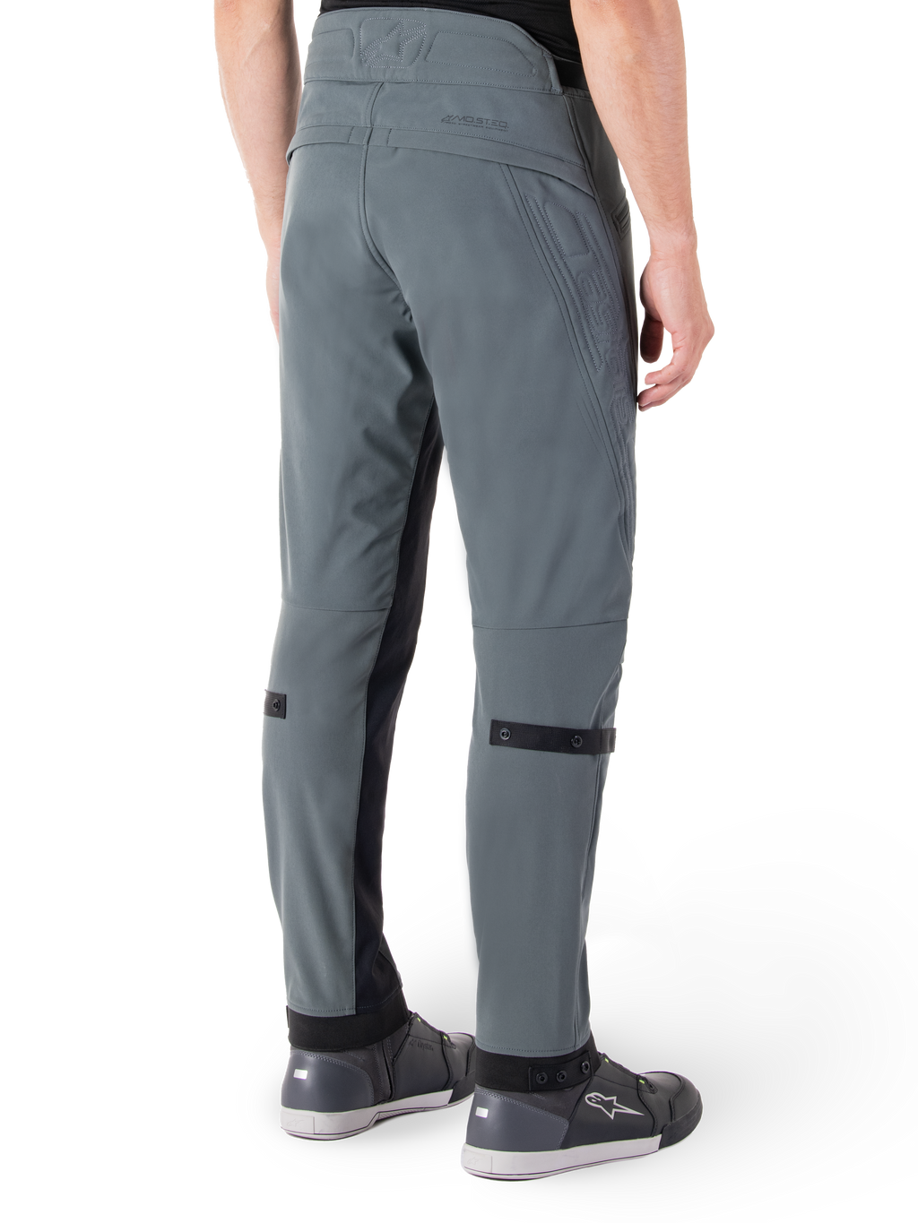 Pantaloni Alpinestars Alden, Urban Gray, vista posteriore laterale, pantaloni tecnici da moto ispirati allo streetwear con dettagli trapuntati sulla vita e cinturini neri sui polpacci, abbinati a scarpe da moto grigie, abbigliamento da moto urbano moderno