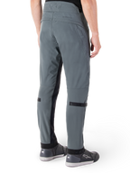 Pantaloni Alpinestars Alden, Urban Gray, vista posteriore laterale, pantaloni tecnici da moto ispirati allo streetwear con dettagli trapuntati sulla vita e cinturini neri sui polpacci, abbinati a scarpe da moto grigie, abbigliamento da moto urbano moderno