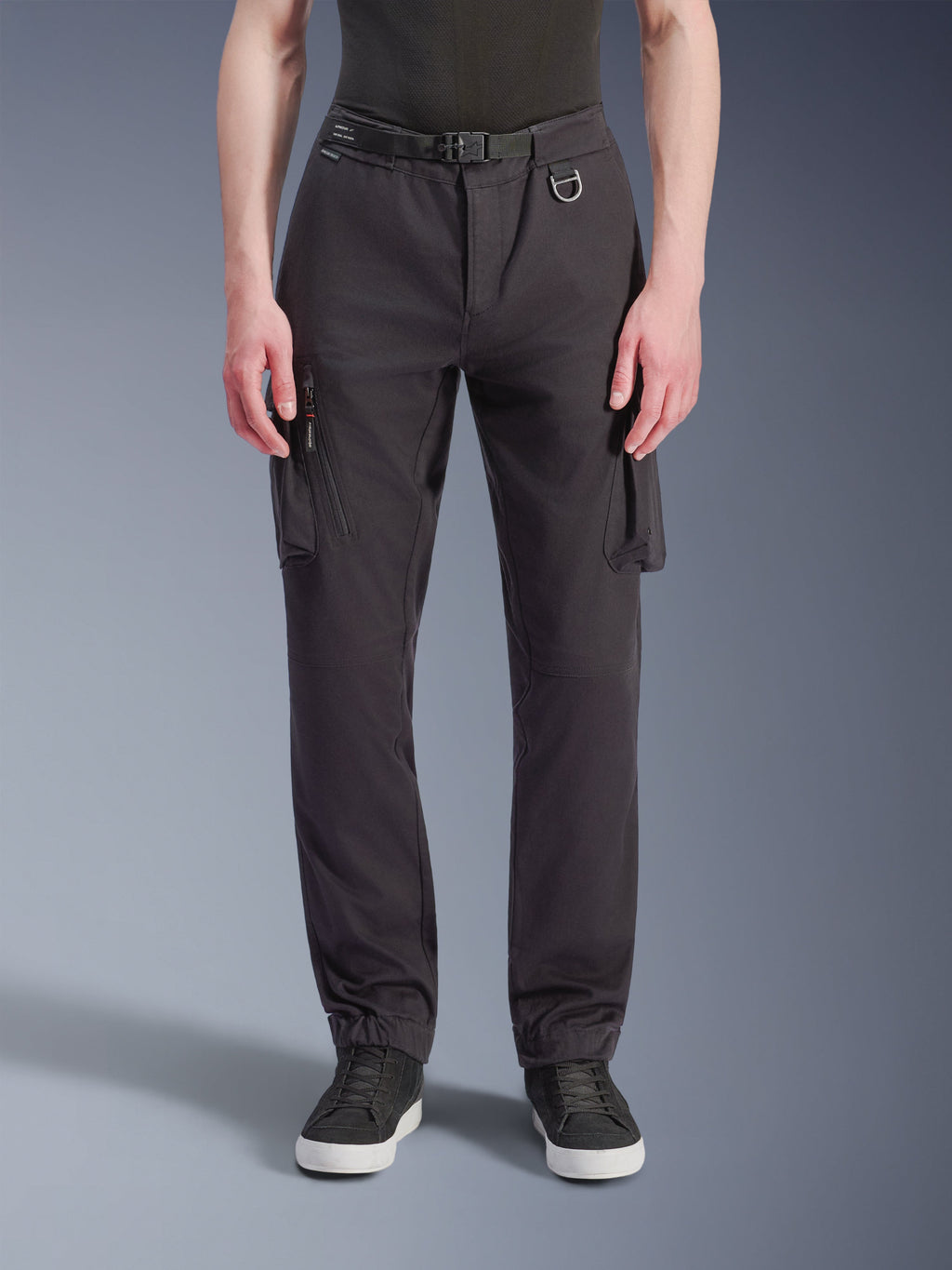 Alpinestars Flex-AST Cargo Pants, pantaloni da moto, nero, vista frontale che mostra la vestibilità regular affusolata, tasche cargo, cintura integrata con anello a D e orli elasticizzati, abbinati a sneaker nere