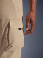 Alpinestars Pantaloni Cargo Flex-AST, pantaloni da moto urbani, beige chiaro, dettaglio ravvicinato della tasca cargo laterale con logo ricamato tono su tono, occhiello in metallo e linguetta nera, tessuto tecnico elasticizzato resistente